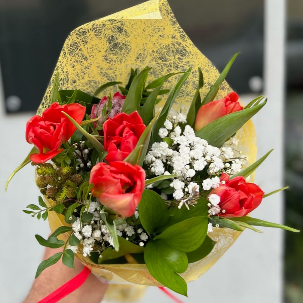 Ramo de rosas rojas con pequeñas flores blancas y bellas hojas verdes