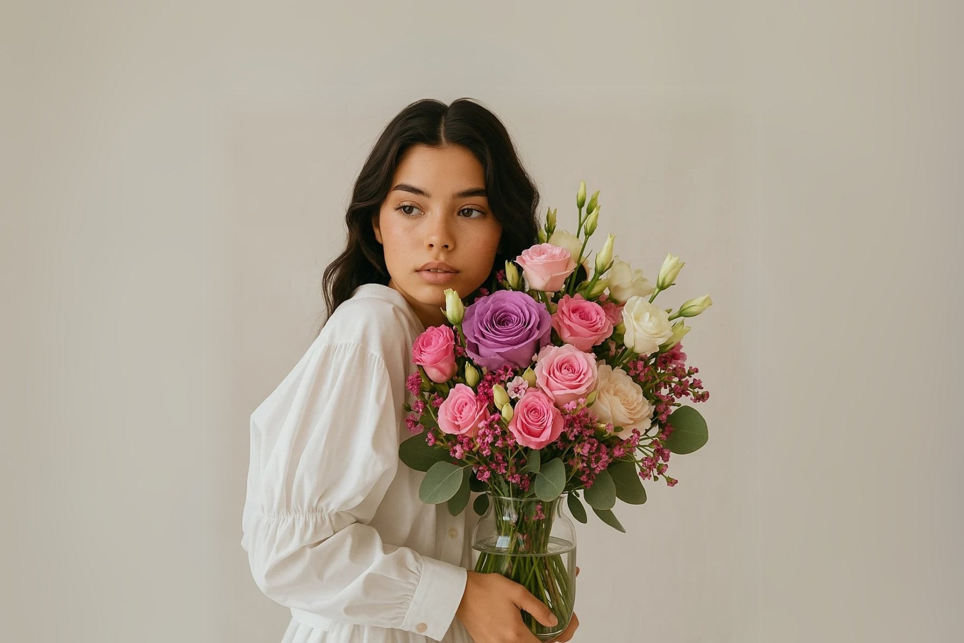 chica guapa sosteniendo un jarron de cristal con el ramo roxana de persa flores