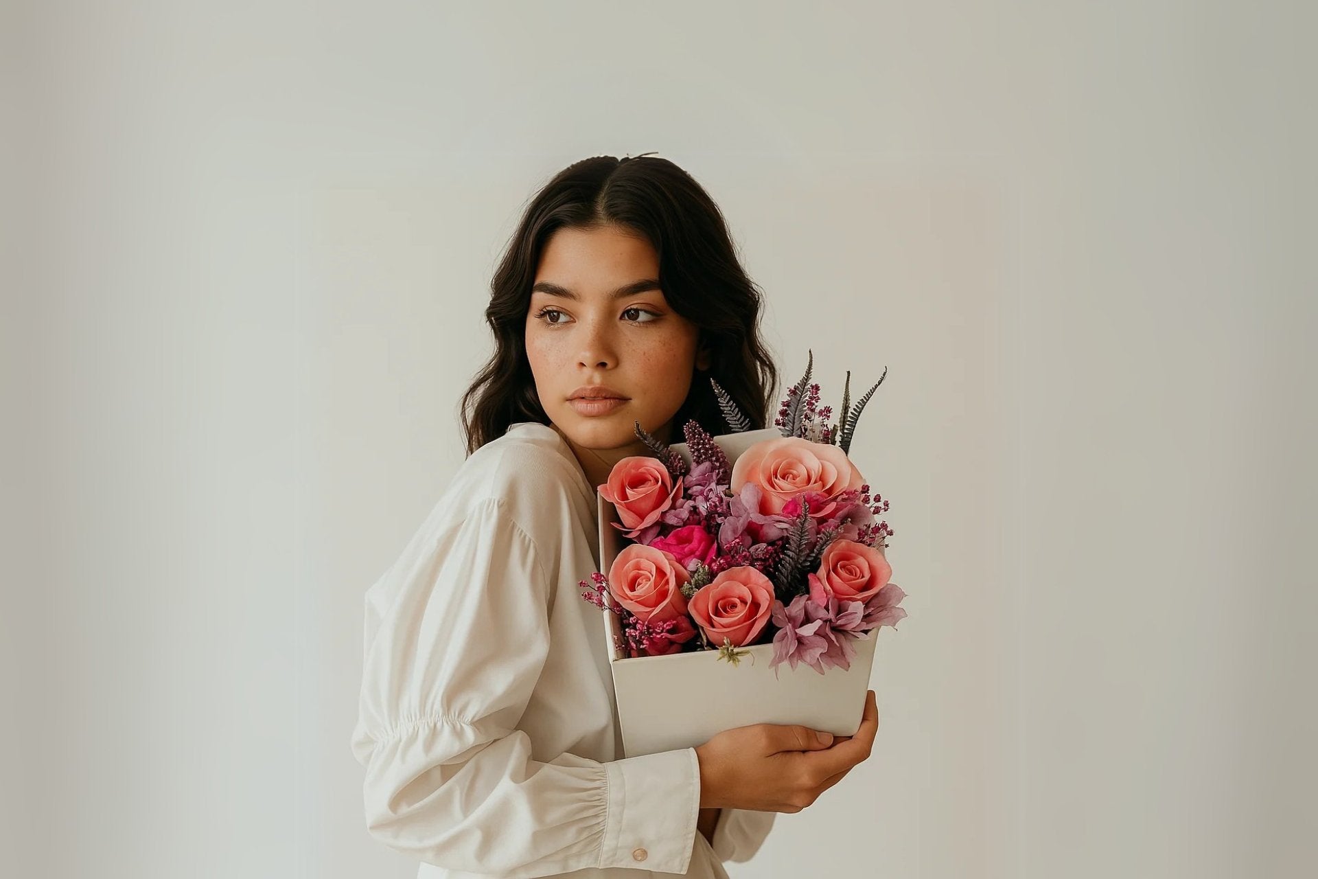 modela joven morena sosteniendo el caja de rosas preservadas de persa flores