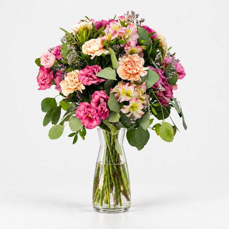 Ramo Andrea con lisianthus rosas, claveles melocotón, alstroemerias y eucalipto en jarrón de cristal Sakura.