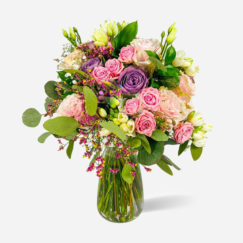 Ramo Roxana con rosas rosadas, lisianthus claros, flores moradas y eucalipto en jarrón de cristal Sakura.